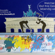 Zwei symbolische Männer hacken mit Spitzhacken auf die Berliner Mauer ein.